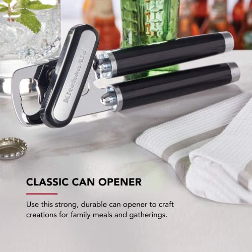 Can opener on a table with glasses and a towel in the background